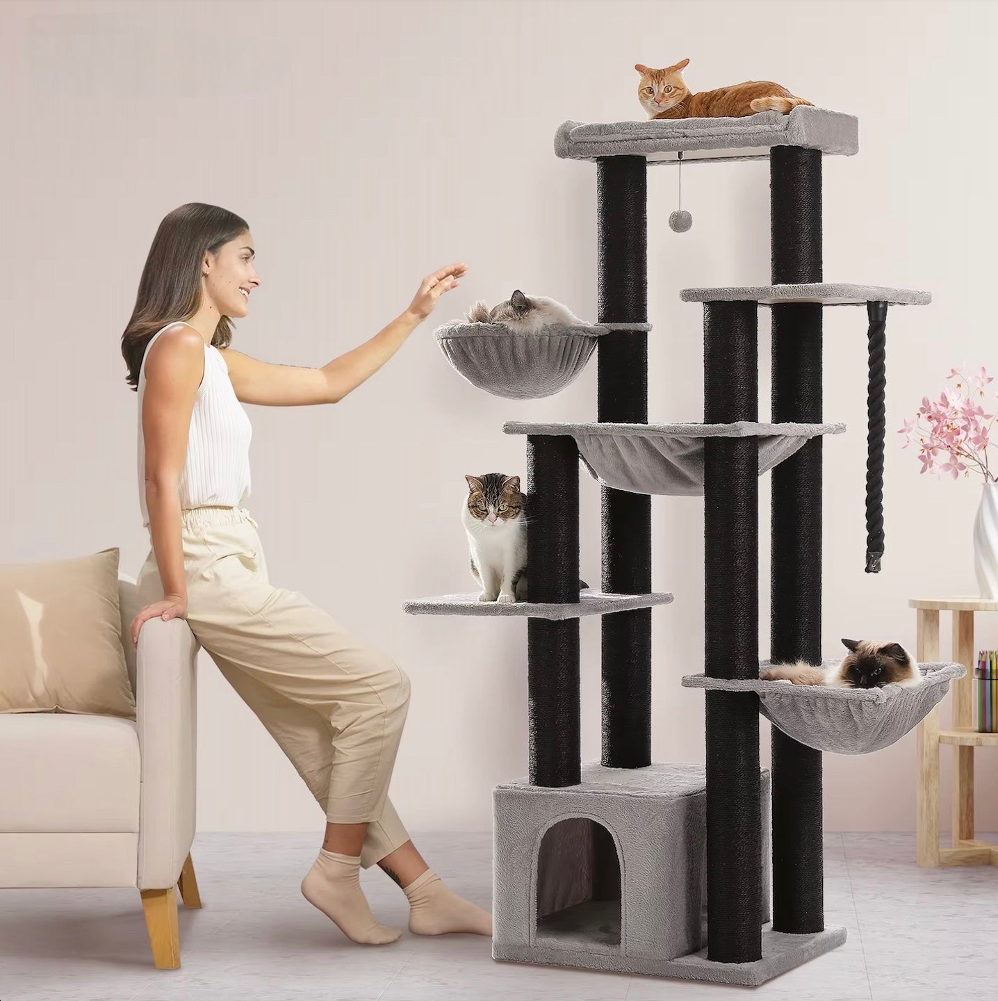De vrouw zit naast de Maine Coon Speeltoren XXL in een binnenomgeving, in zwart en grijs kleur