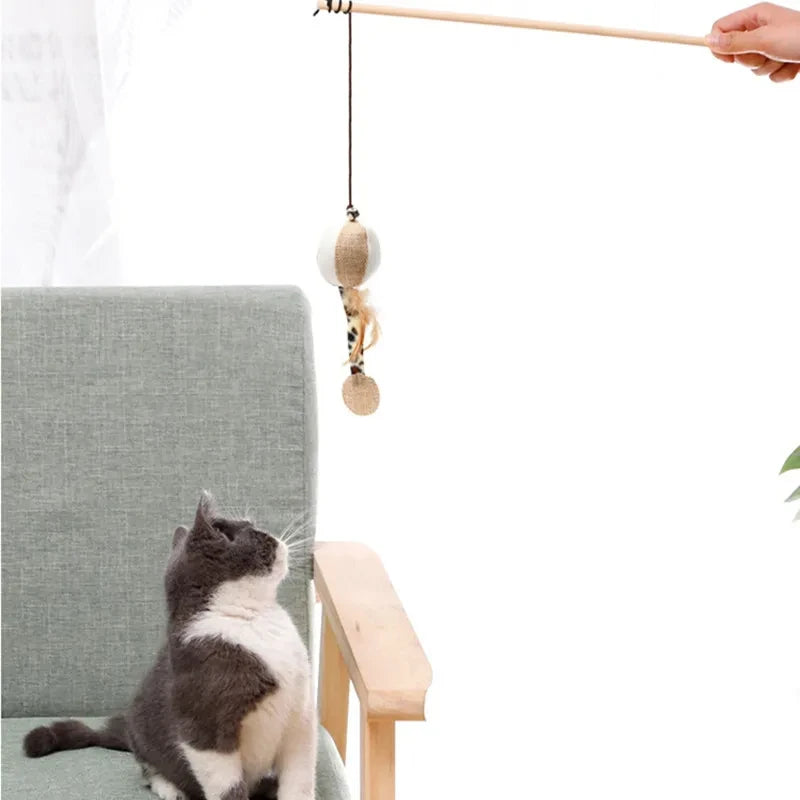 Een kat geniet van speeltijd met de Klassieke Speelhengel—een charmant houten speeltje versierd met kleurrijke veren