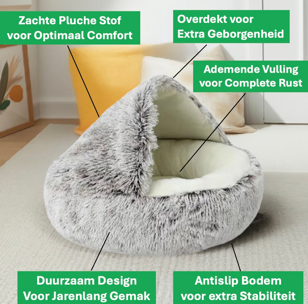 Een zachte, bruine kattenmand van fluffy materiaal staat op een grijs tapijt. De mand heeft een ronde vorm en dikke opstaande randen voor extra comfort. Het pluche materiaal oogt warm en luxe. De setting straalt rust en huiselijkheid uit.